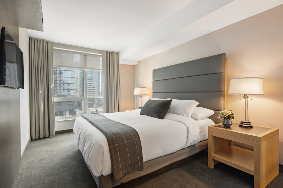 A quiet, softly lit hotel room interior with a large window overlooking a darkened city skyline