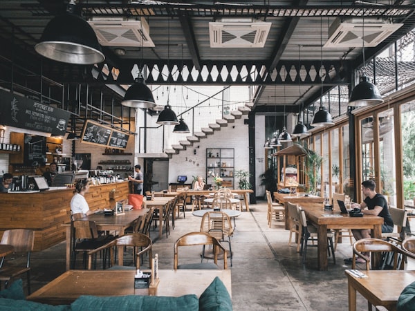 An empty restaurant dining room with warm pendant lighting and neatly set tables